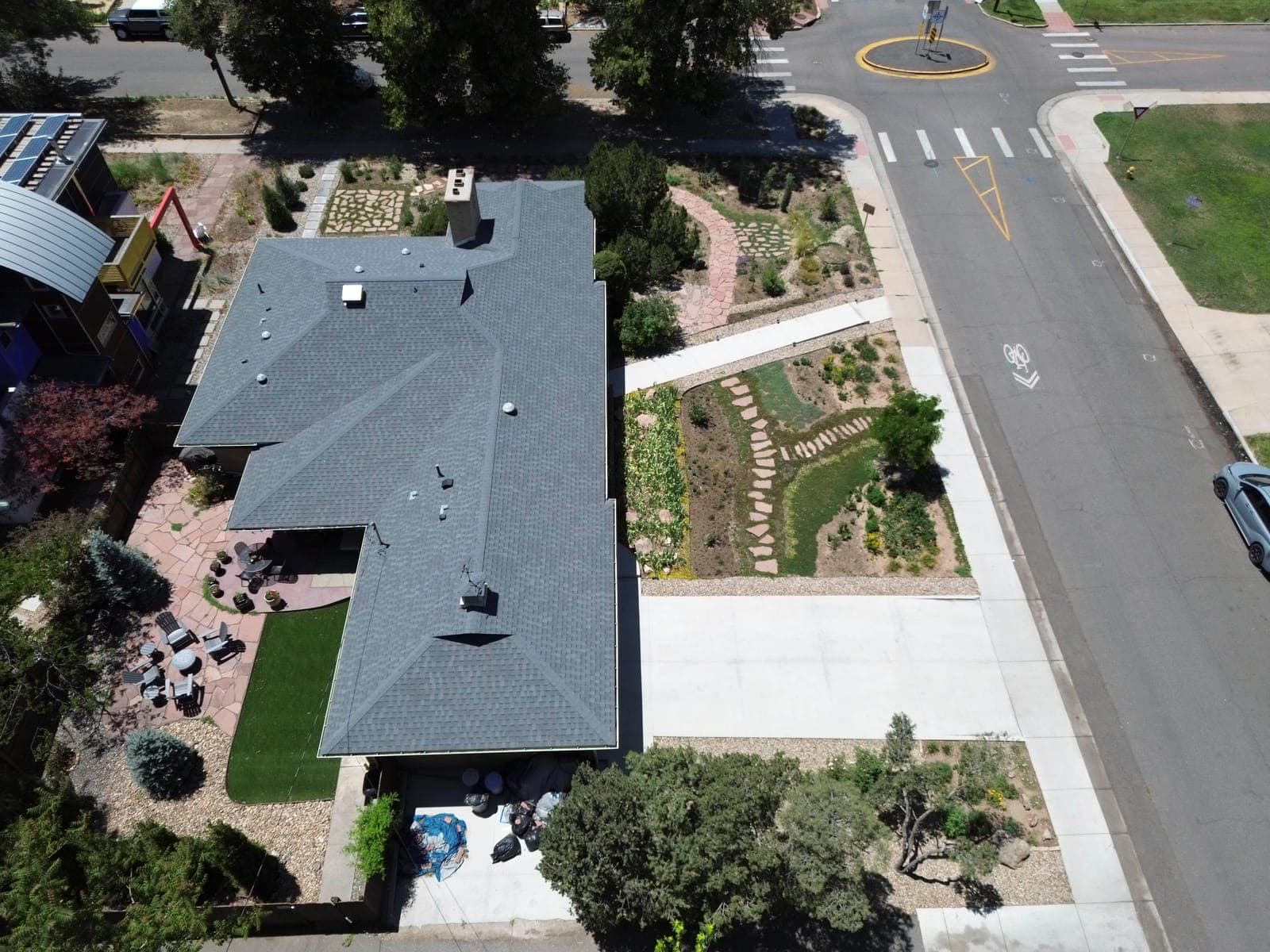 Aerial view of the corner lot showing the roofline, rear patio areas, and front garden beds