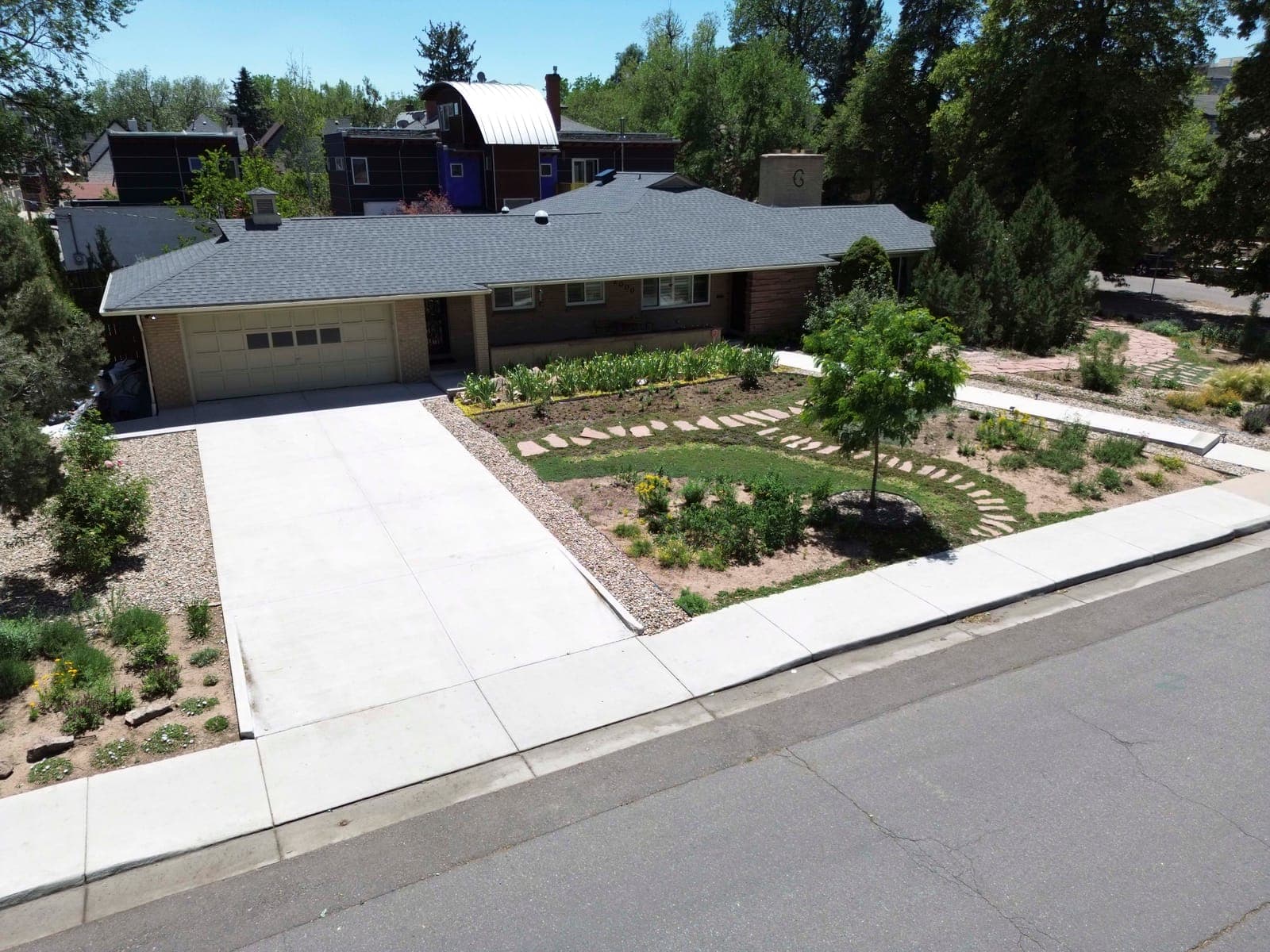 Elevated front view with the garage, brick facade, and layered front garden plantings