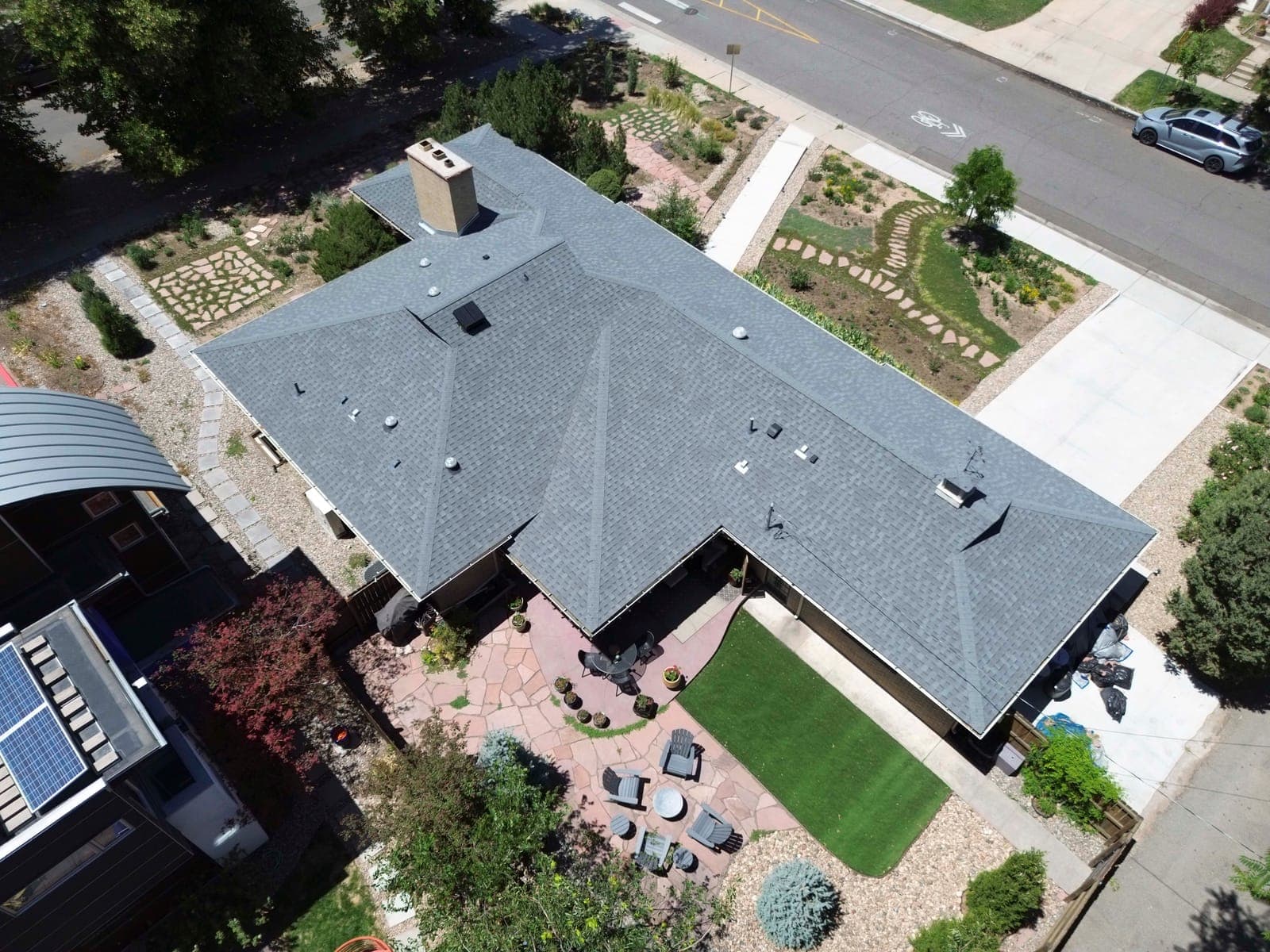 Aerial view of the rear yard with the flagstone patio, turf panel, and mature evergreens