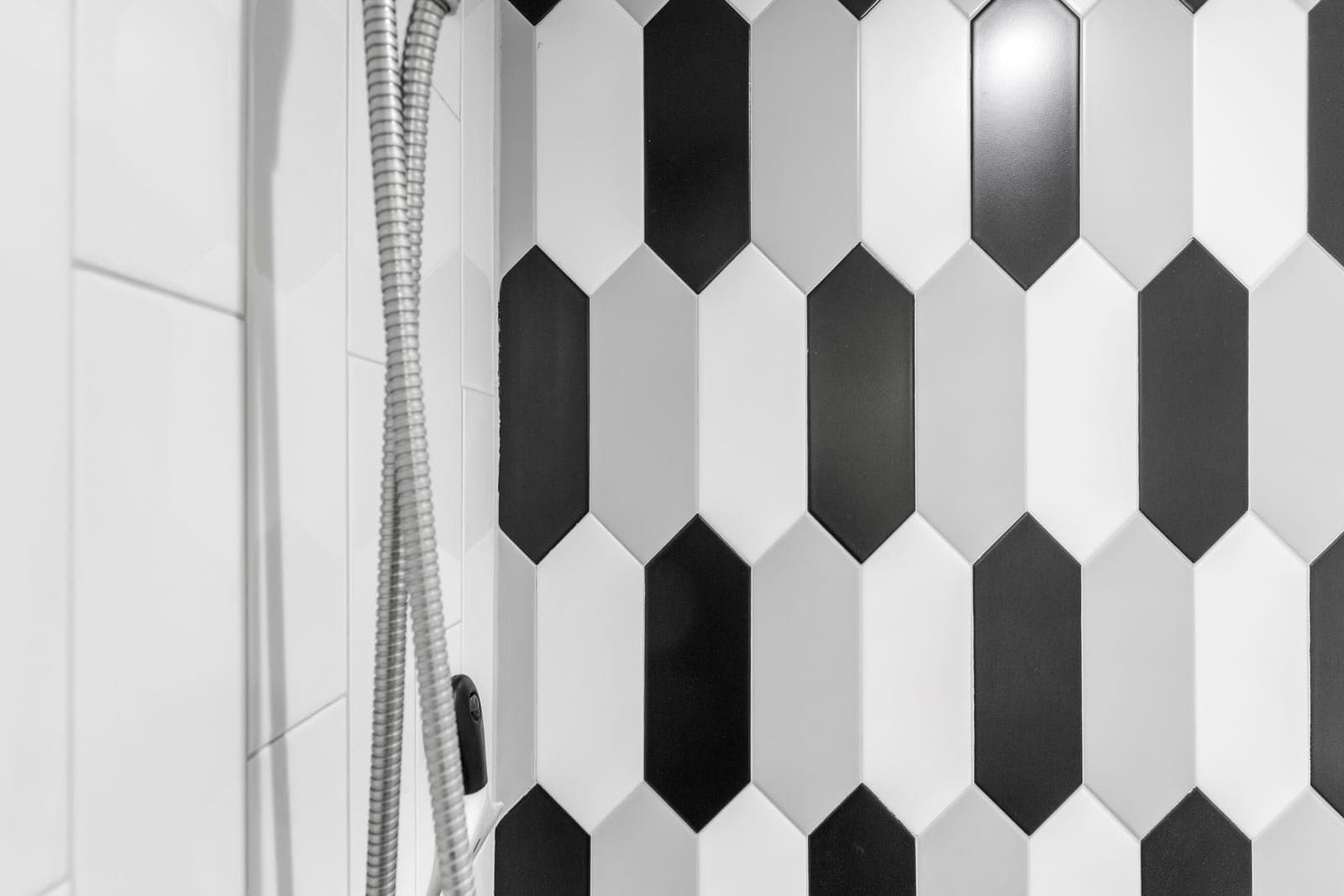 Shower wall in alternating black, white, and grey picket tile