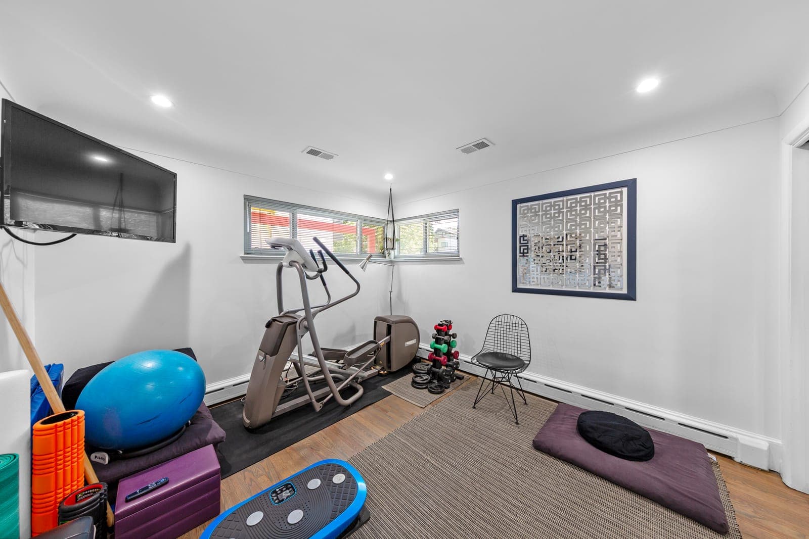 Bedroom staged as a workout room with corner windows and geometric screen art