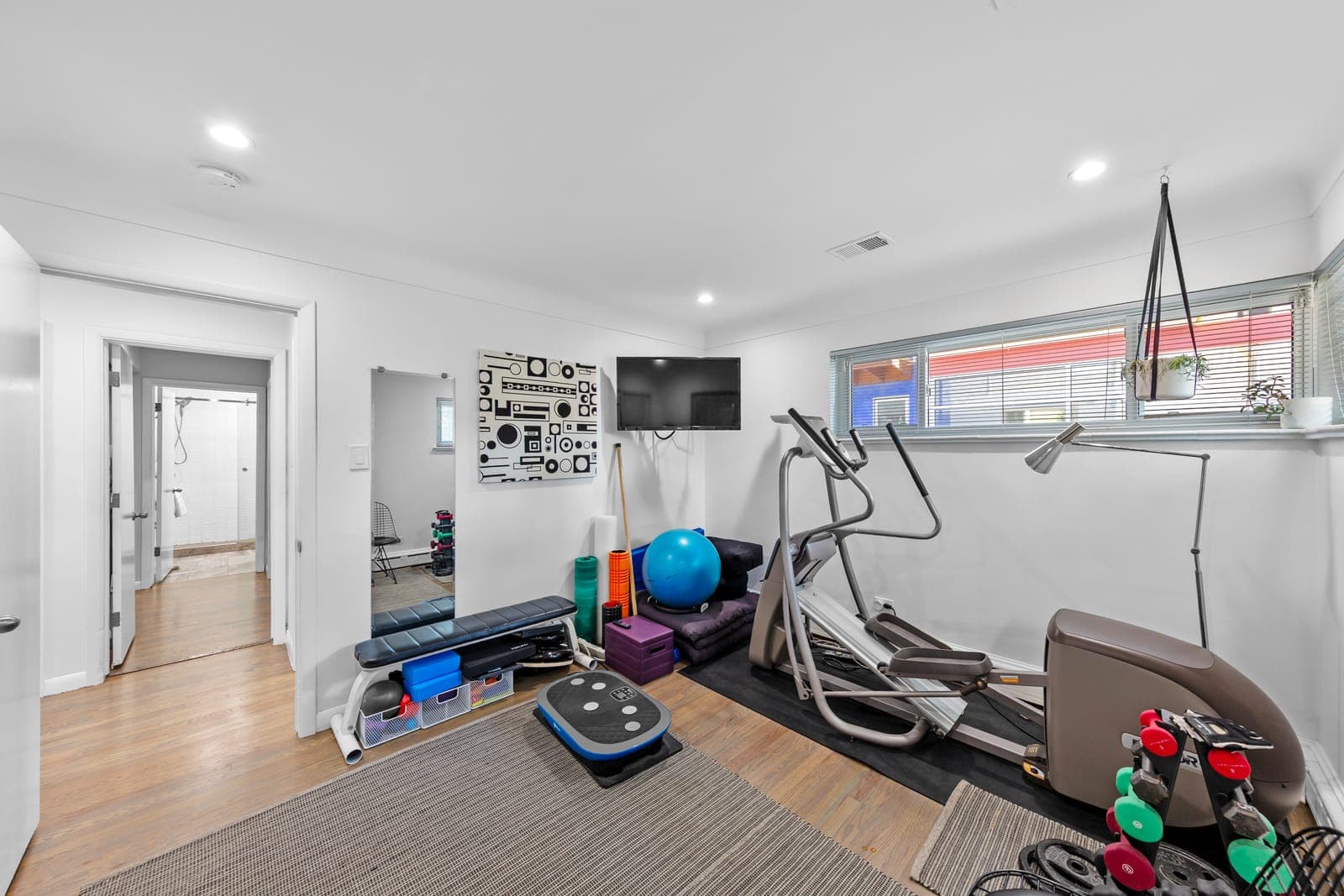 Bedroom staged as a workout room, looking toward the hallway and bathroom