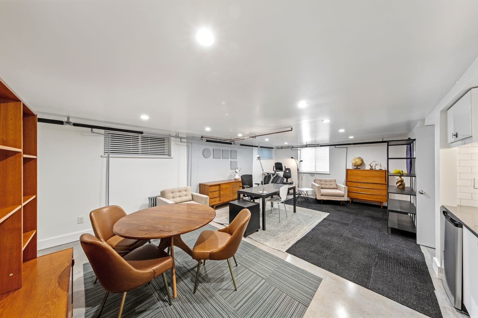 Finished lower level with a round walnut table, leather chairs, and a work area beyond