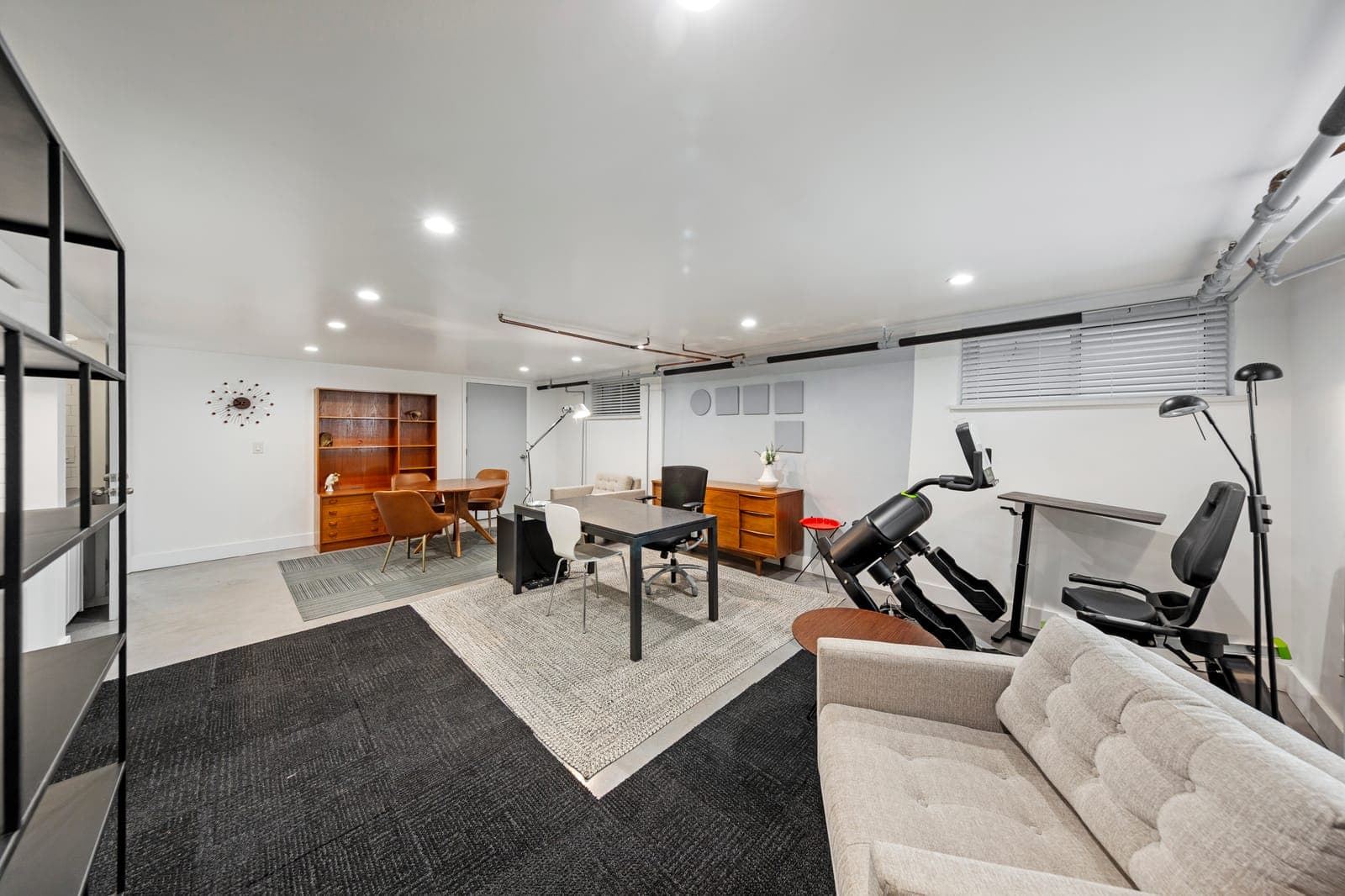 Lower-level lounge and office area with walnut credenzas and a tufted sofa