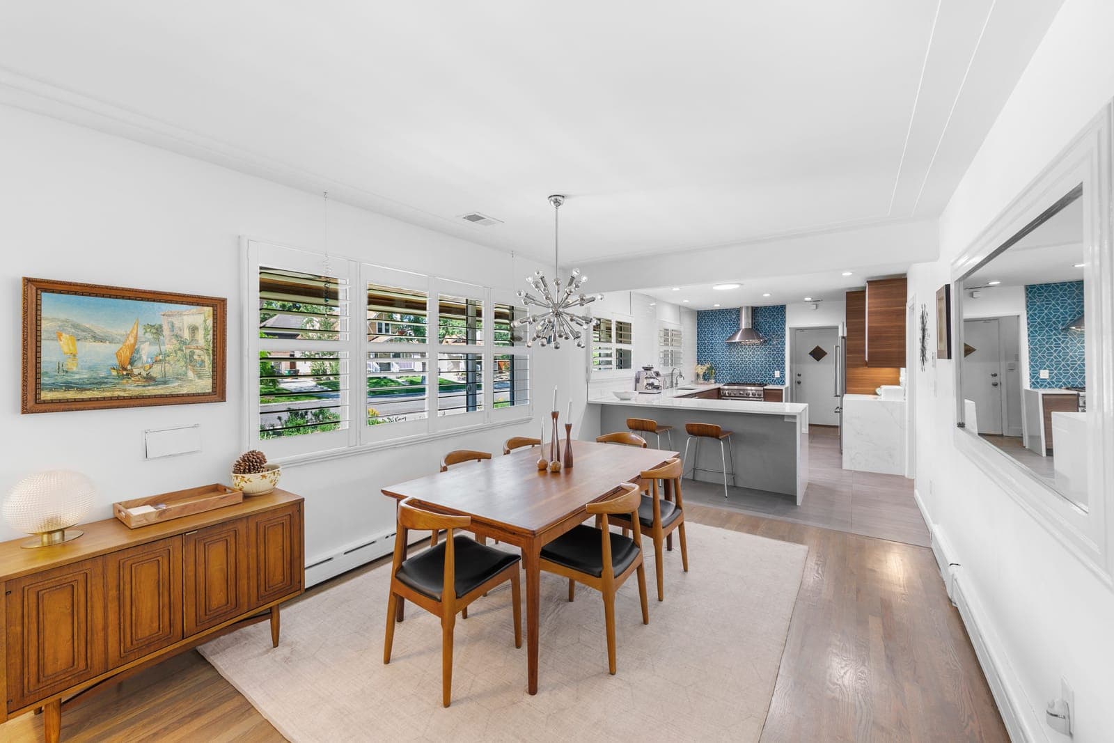 Open dining room and kitchen with a quartz peninsula and chrome sputnik chandelier