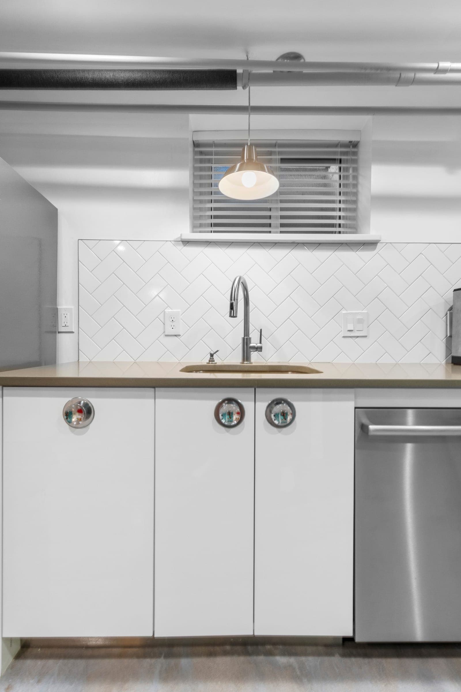 Kitchenette with a herringbone tile backsplash, quartz counter, and dome pendant light