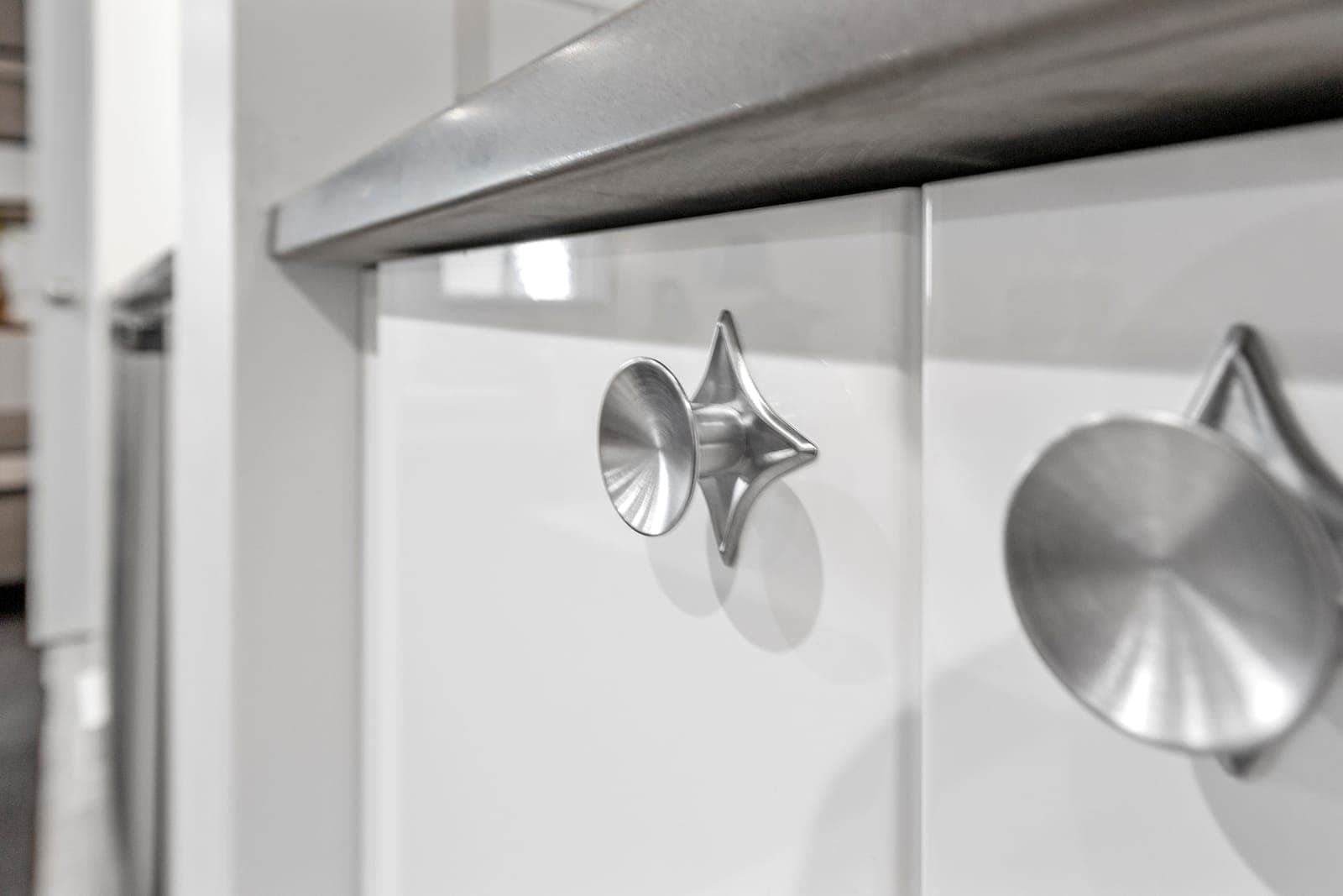 Brushed-metal atomic star cabinet knob on white cabinetry