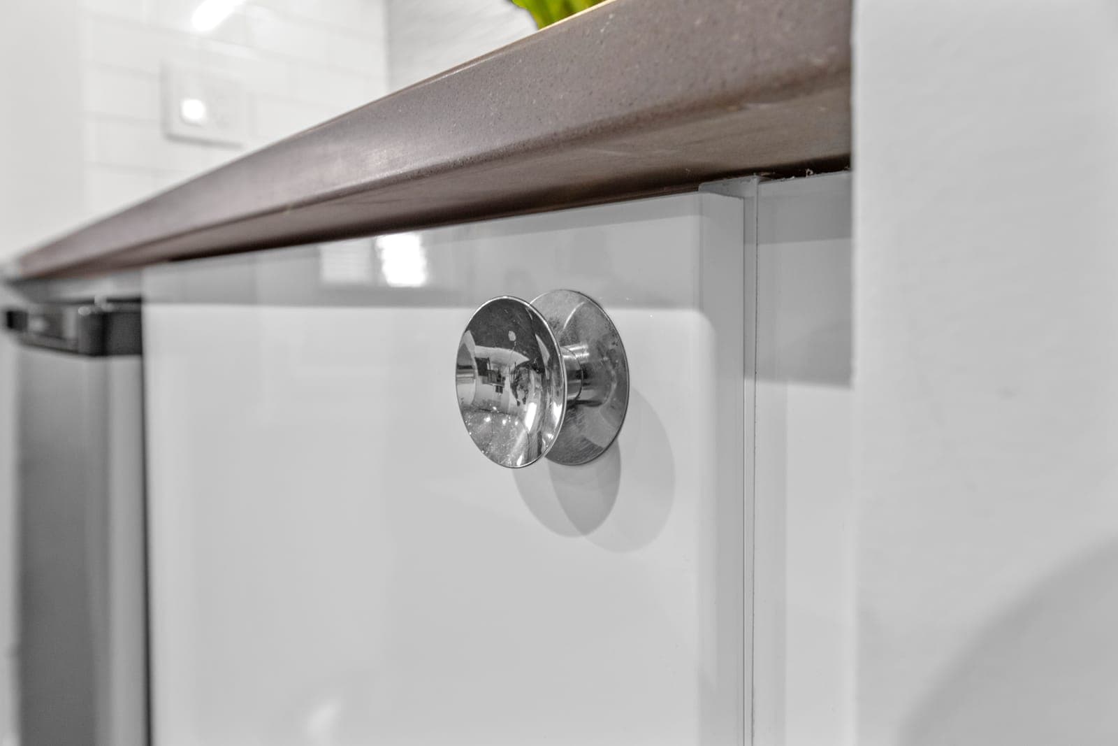 Polished round cabinet knob against a grey quartz counter edge
