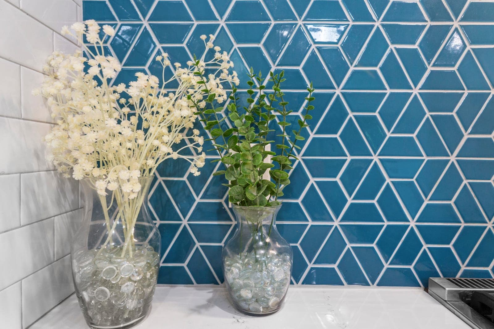 Blue geometric tile backsplash meeting white subway tile at the kitchen counter