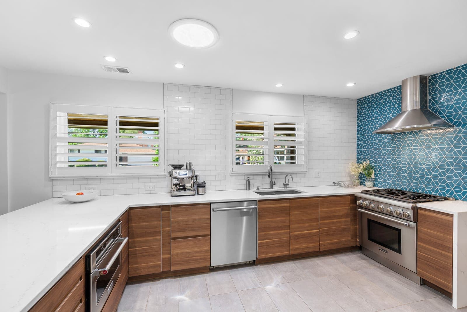 Kitchen sink and range wall with white subway tile, quartz counters, and walnut cabinets