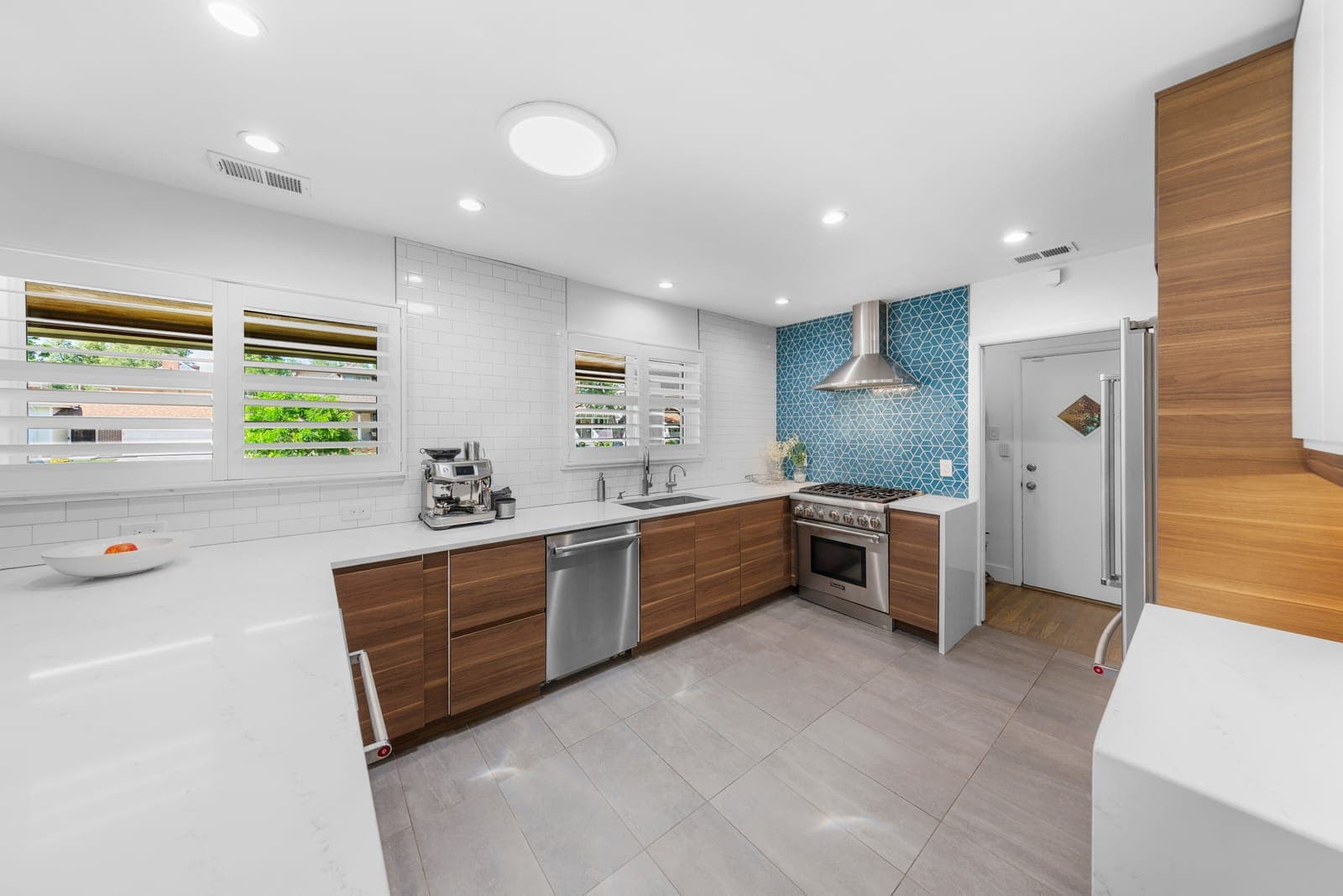 Kitchen with a professional gas range, walnut cabinetry, and blue geometric tile backsplash