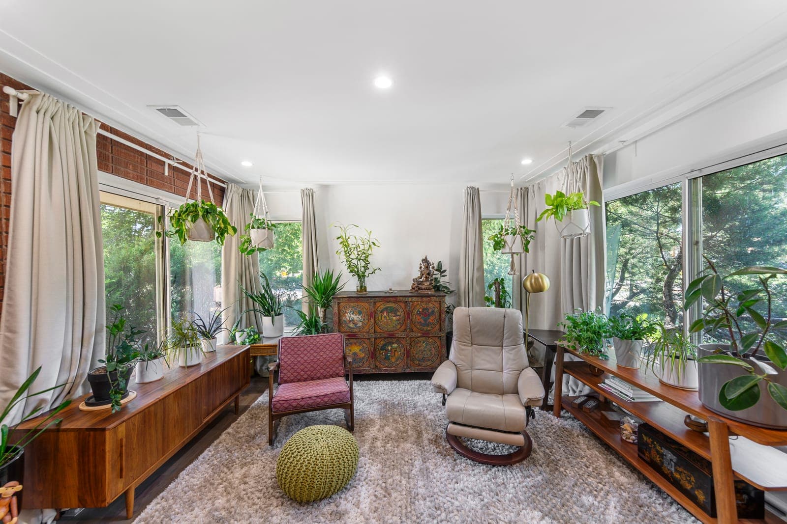 Sunlit sitting area with wrap-around corner windows and low walnut credenzas