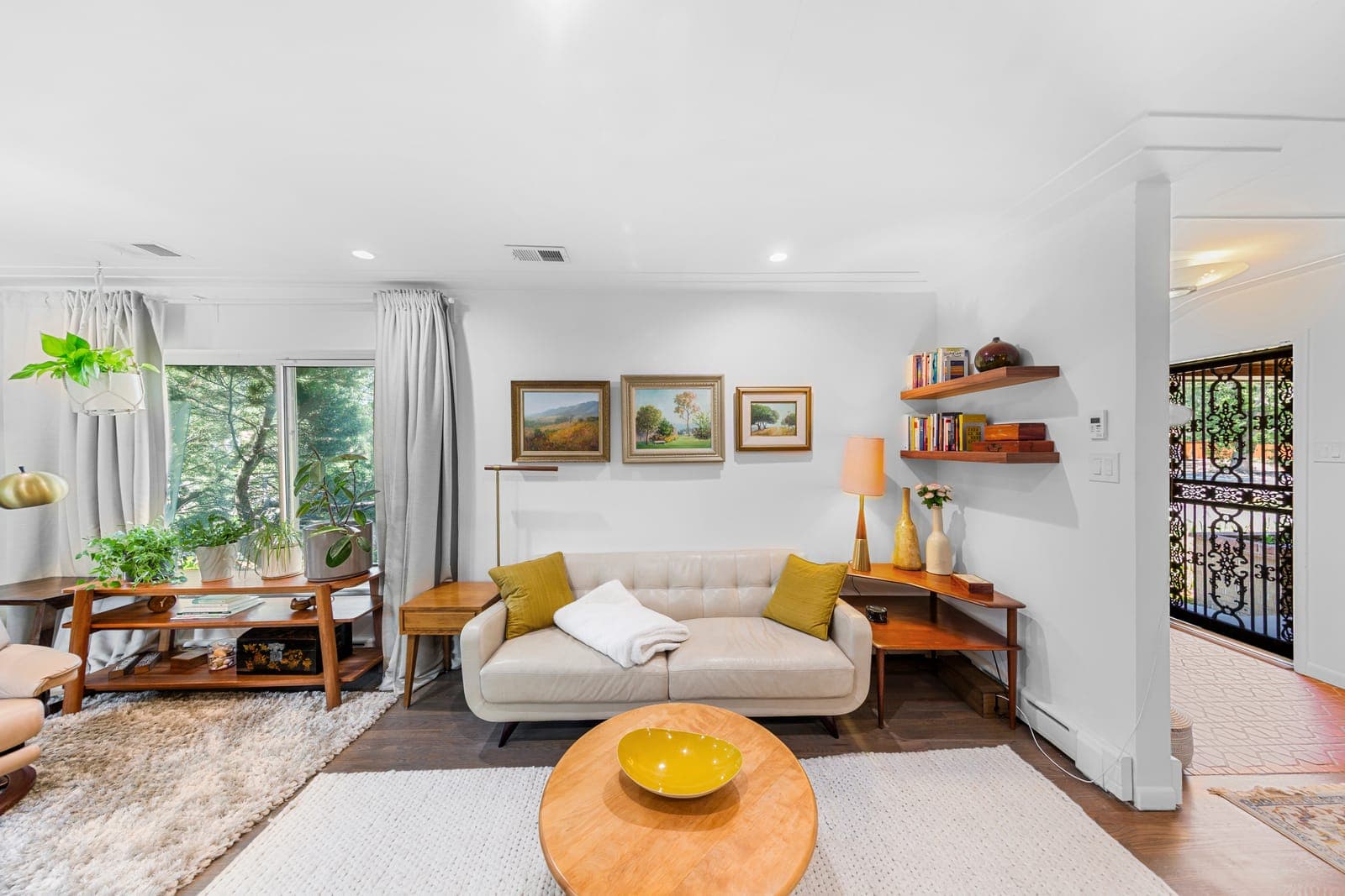 Living room seating area with floating walnut shelves and a framed landscape gallery wall