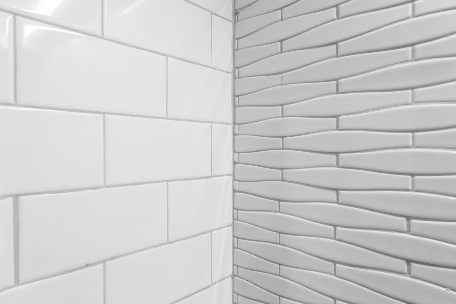 Corner detail where white subway tile meets the sculpted wave-tile wet bar wall