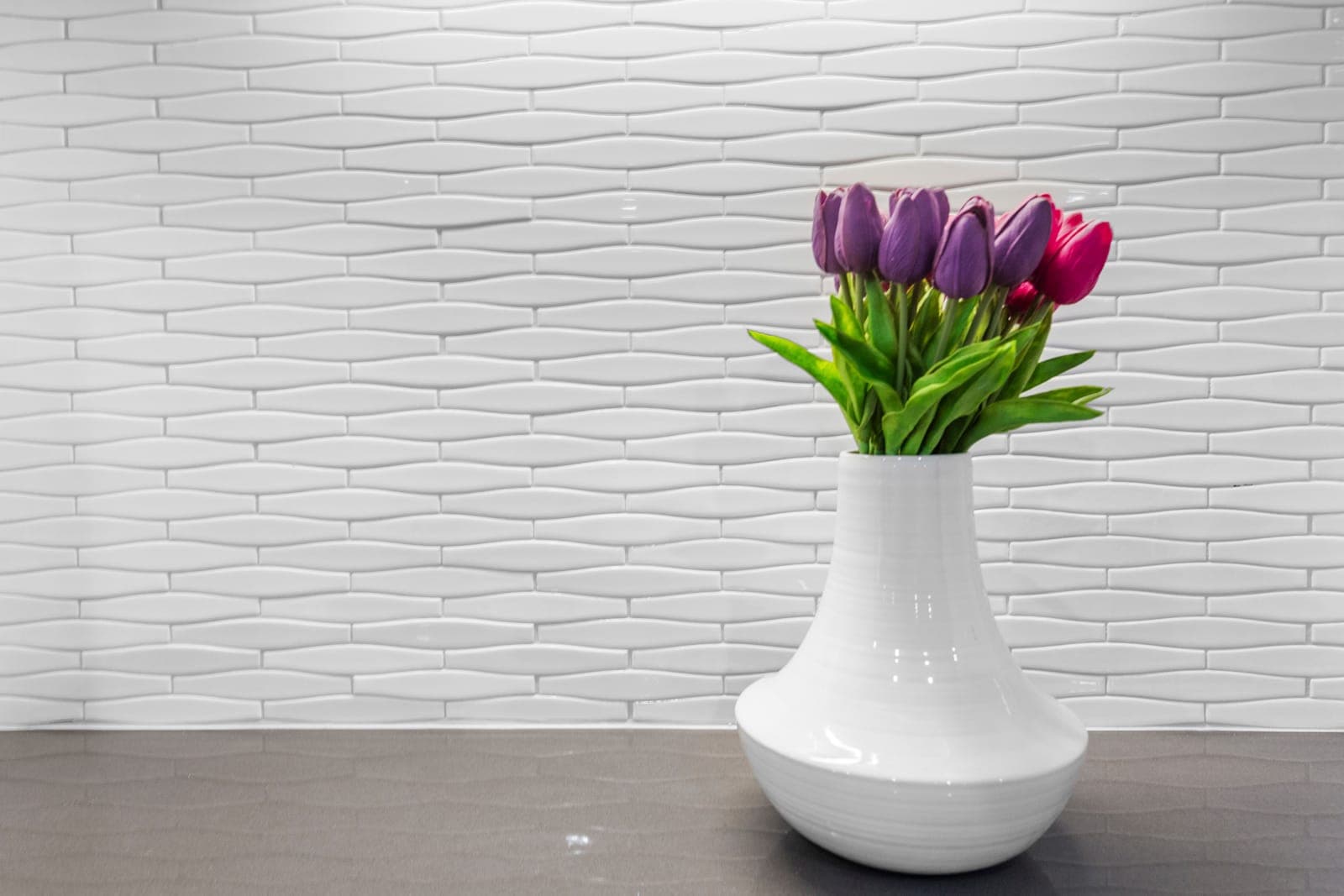 Wet bar counter vignette with a dimensional wave-tile wall and grey quartz surface