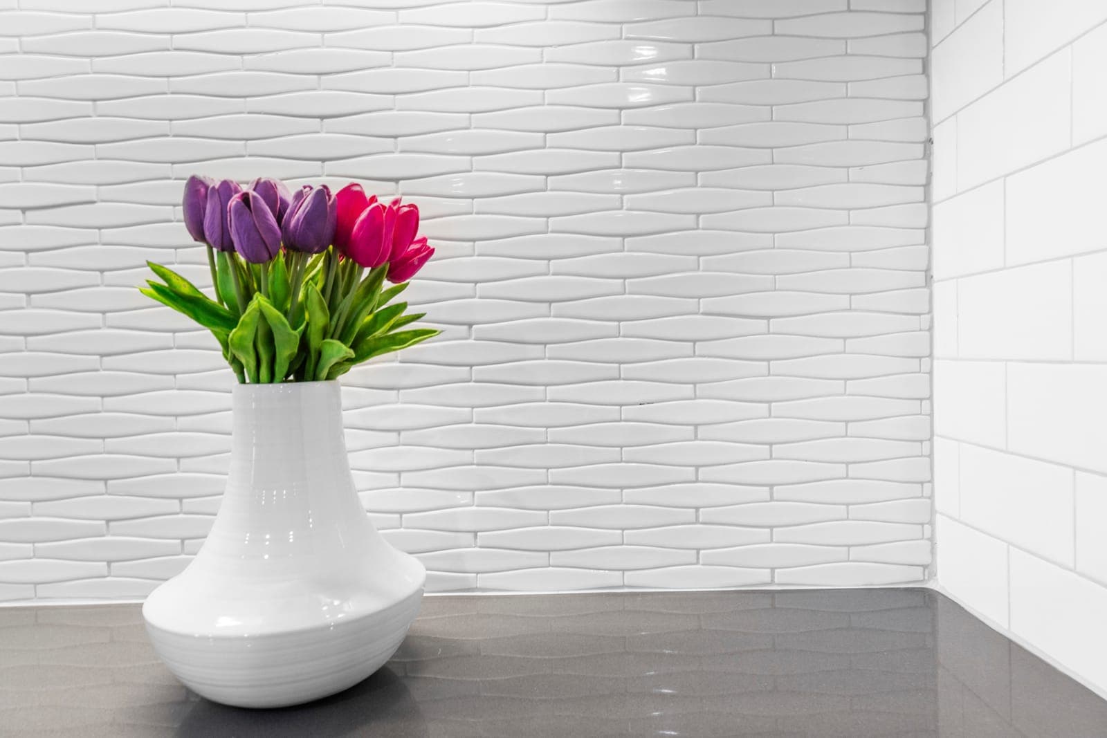 Wave-pattern tile wall meeting white subway tile above the wet bar counter
