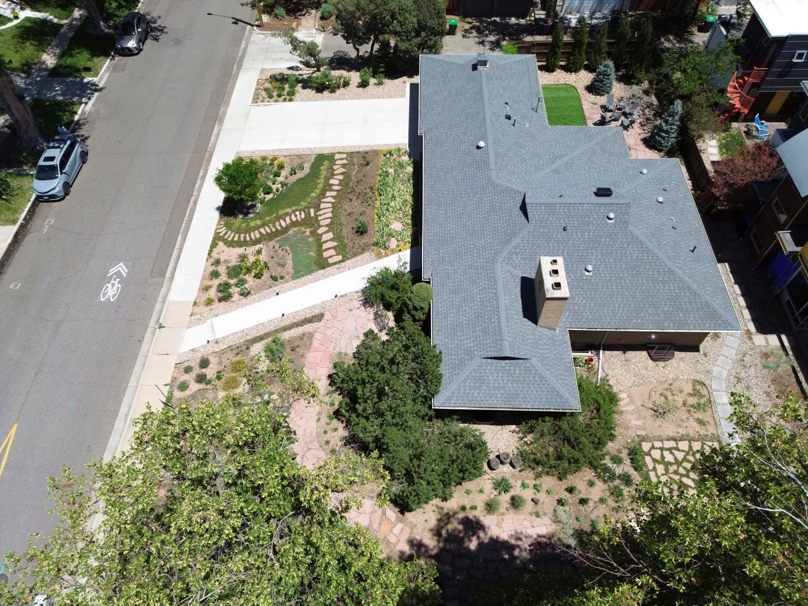 Overhead view of the low-slung roofline, front gardens, and flagstone paths on the corner lot