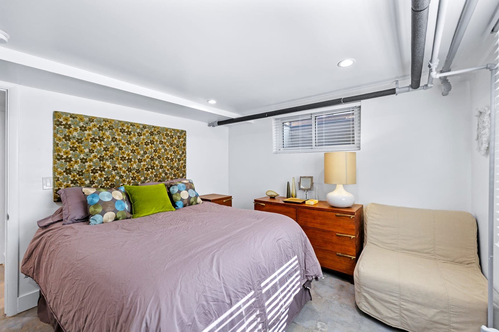 Lower-level bedroom with a floral upholstered headboard panel and walnut dressers