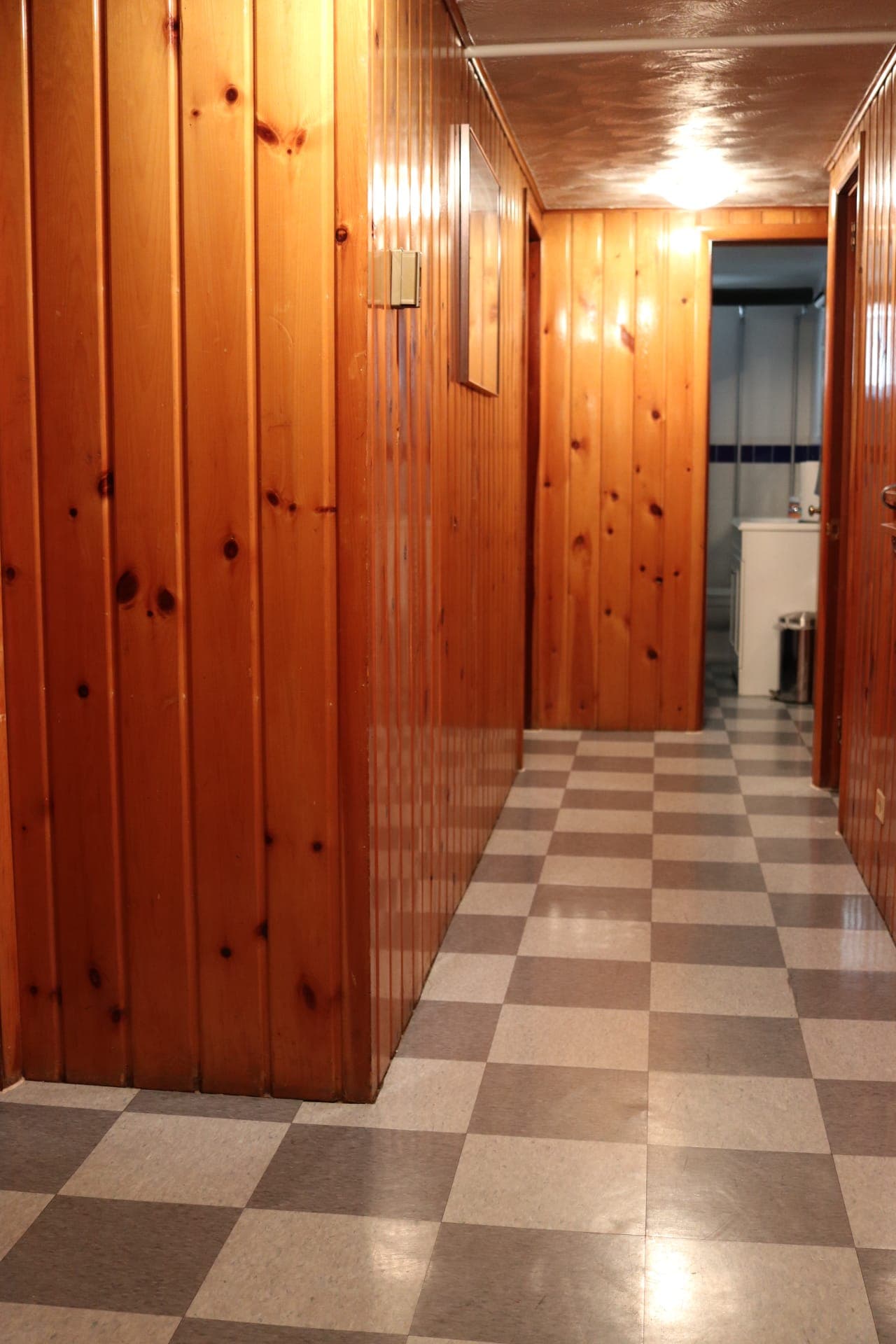 Knotty-pine paneled basement hallway with checkerboard tile