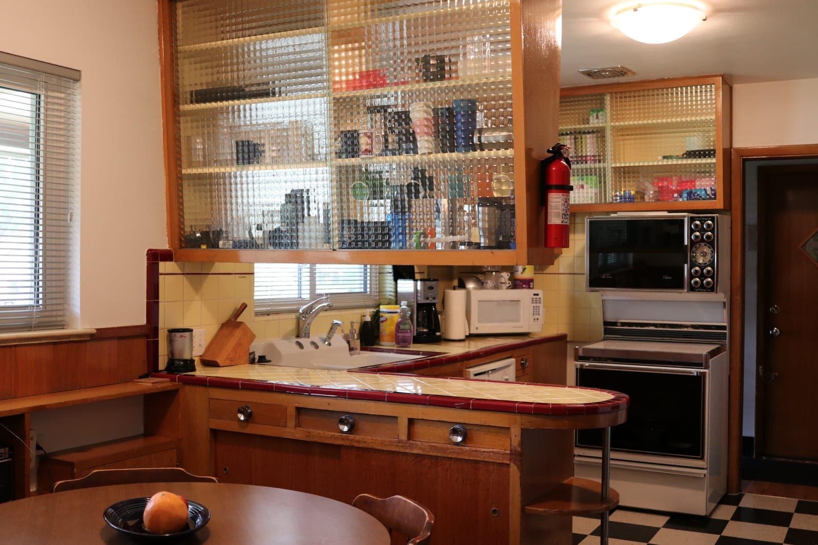 The original 1950s kitchen with textured-glass upper cabinets and yellow tile counters