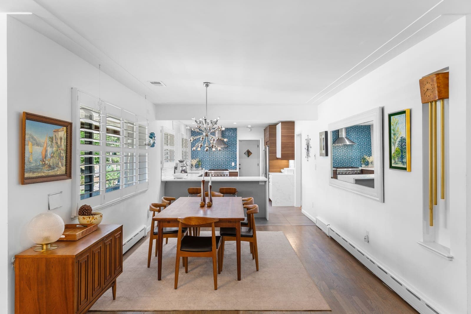 Dining room with plantation shutters and a sputnik chandelier, open to the kitchen