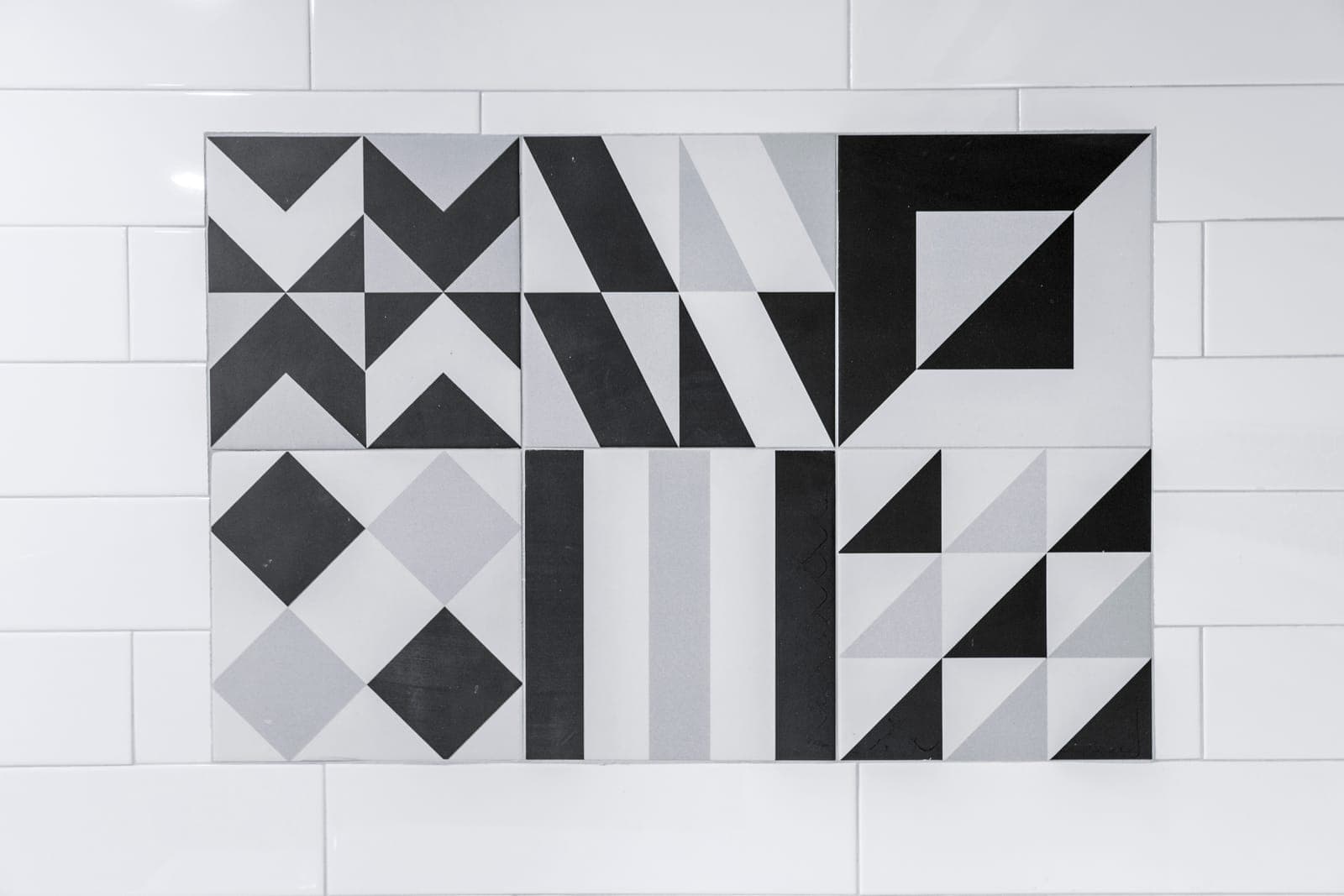 Framed panel of black, white, and grey geometric patterned tiles