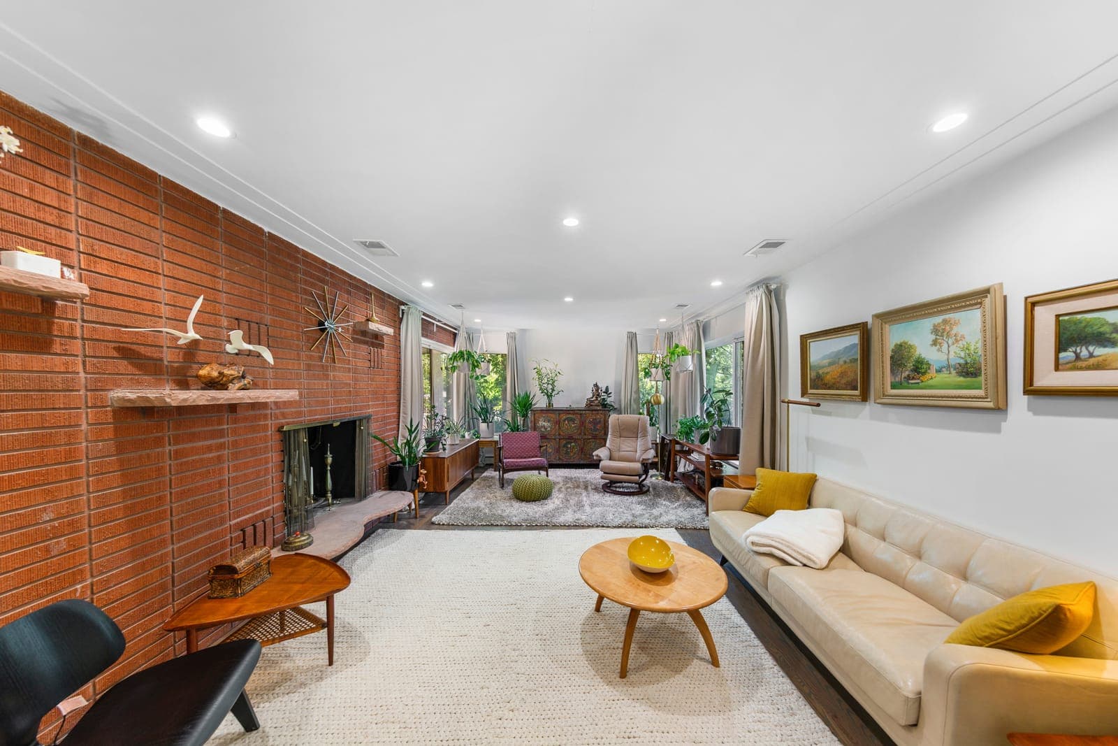 Living room with a full-height brick fireplace wall, floating stone shelves, and a starburst clock