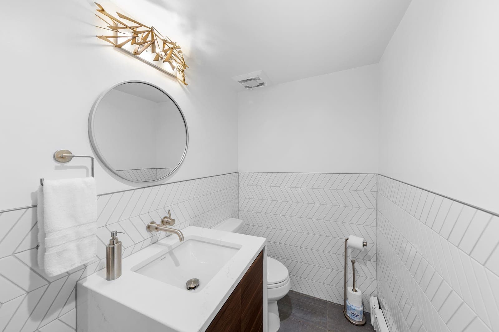 Powder bath with chevron tile wainscot, walnut vanity, and a brushed nickel wall-mounted faucet